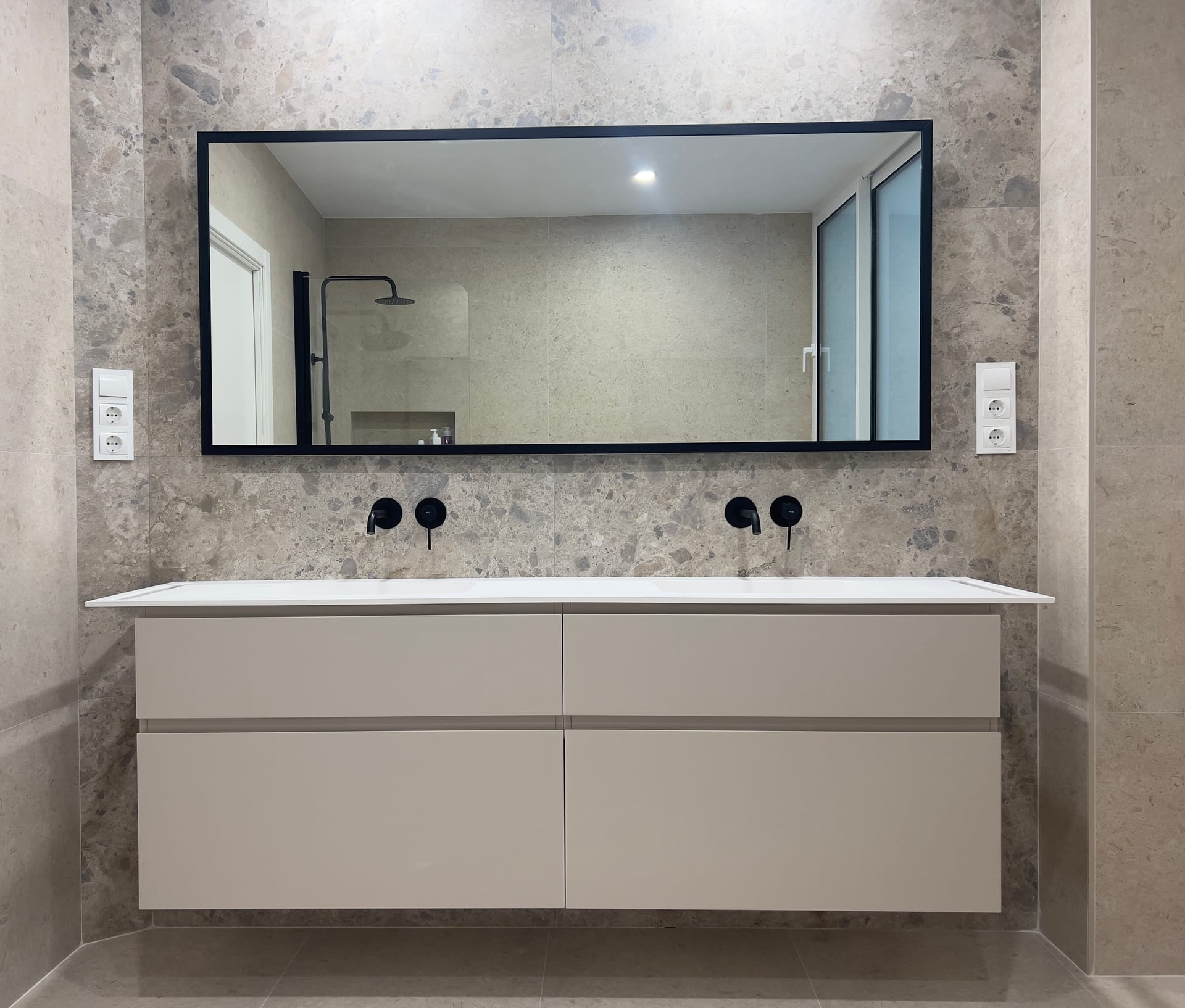Mueble de doble lavabo con encimera blanca y grifería mural negra