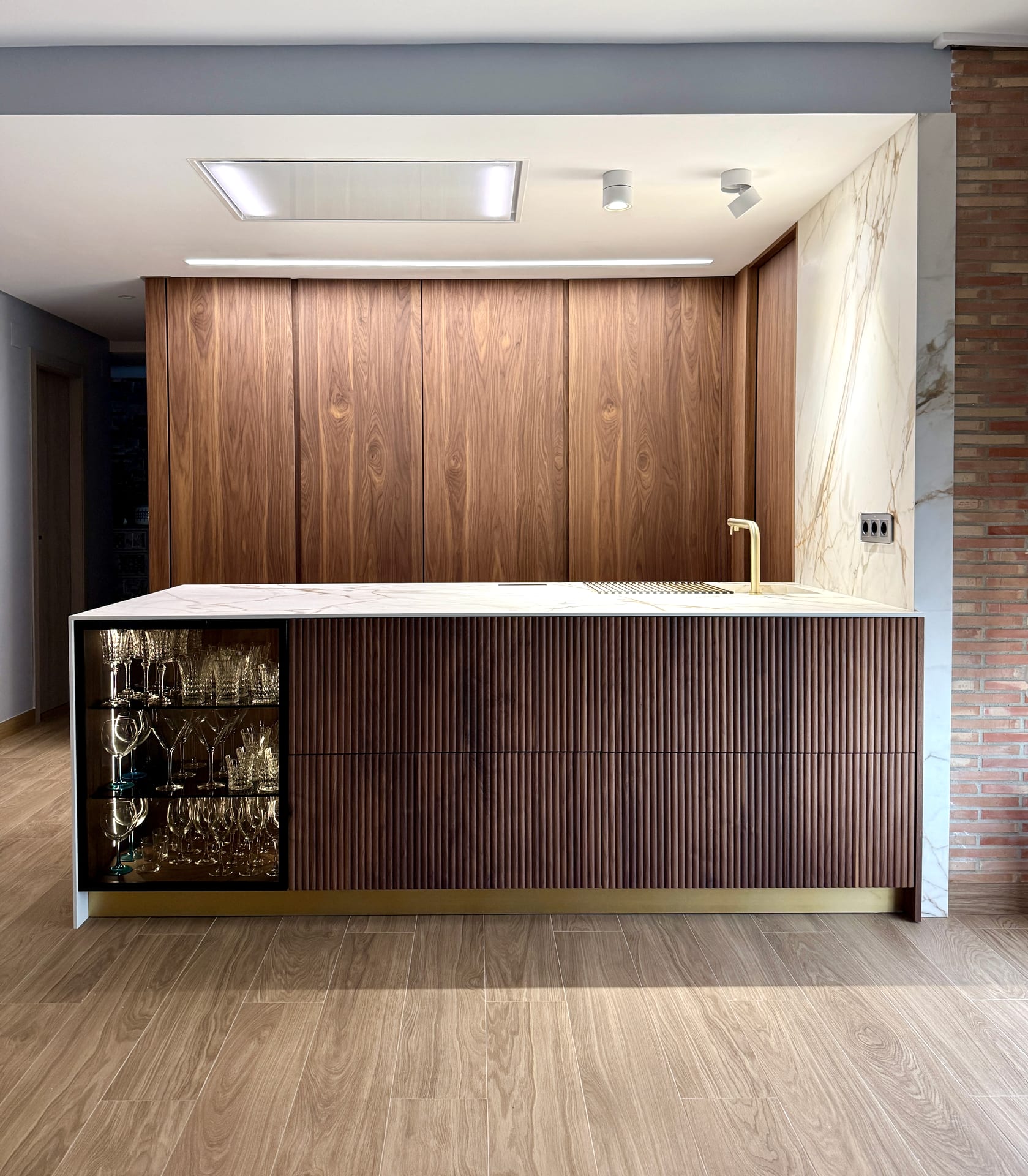 Frente de cocina en madera de nogal con isla y vitrina retroiluminada