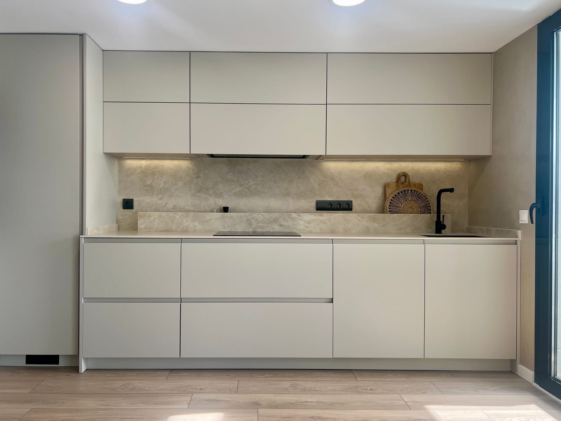 Frente de cocina con muebles mate, encimera clara e inducción