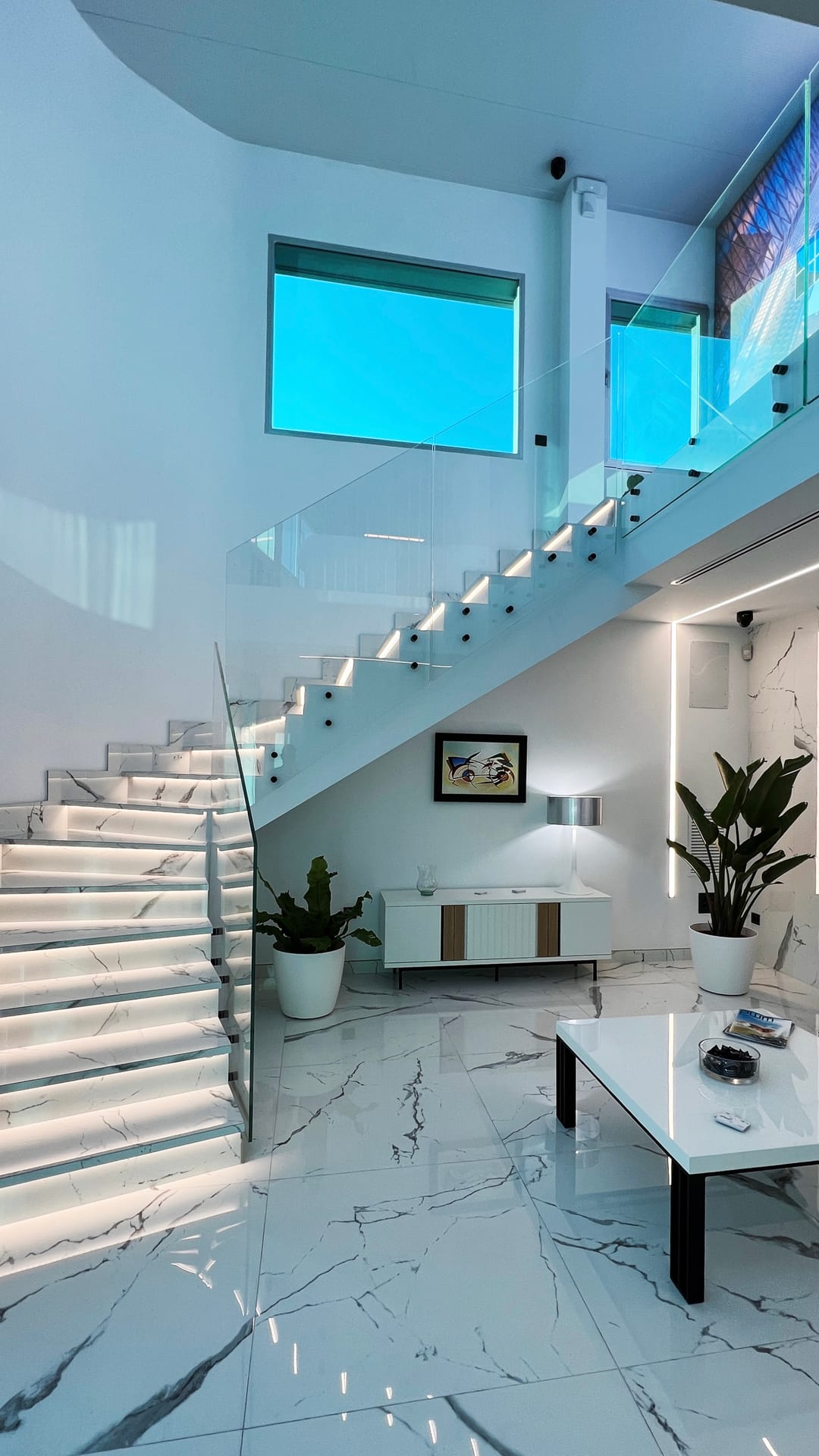 Doble espacio de entrada con escalera retroiluminada y zona de estar